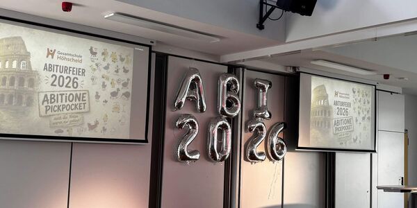 Das Abiturmotto ist an zwei Projektionswänden angeworfen. In der Mitte sind Luftballons mit dem Schriftzug Abi 2026 aufgehangen.