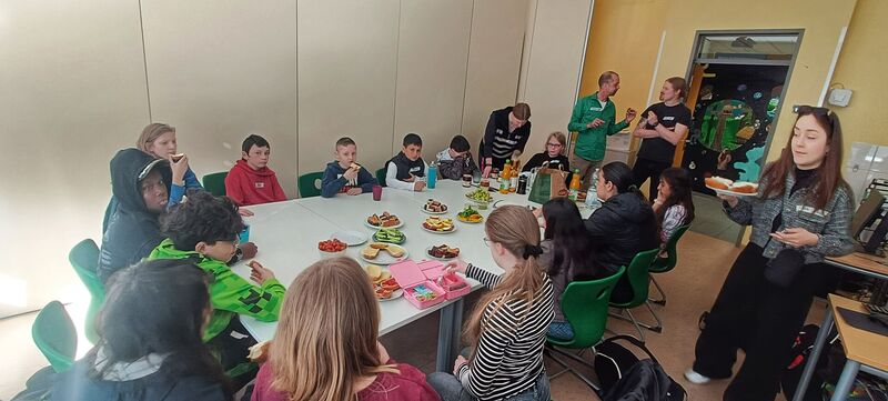 Rund 20 Kinder frühstücken an einem großen Tisch miteinander zur Begrüßung Begrüßung neue Kinder an der Gesamtschule Höhscheid