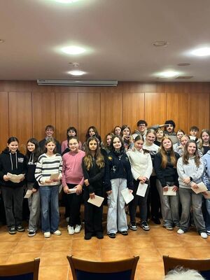 Schülerinnen und Schüler haben in einem Saal gerade ein Weihnachtslied gesungen und lächeln in die Kamera.