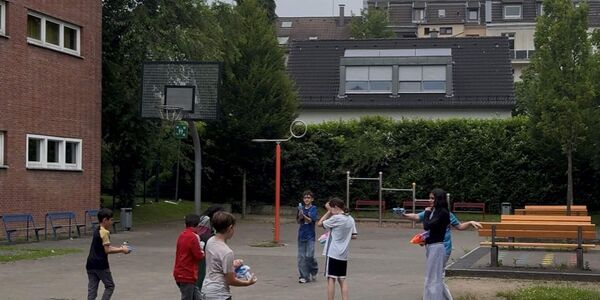 Mit Wasserpistolen und Wasserbomben machen sich acht Schülerinnen und Schüler gegenseitig nass.