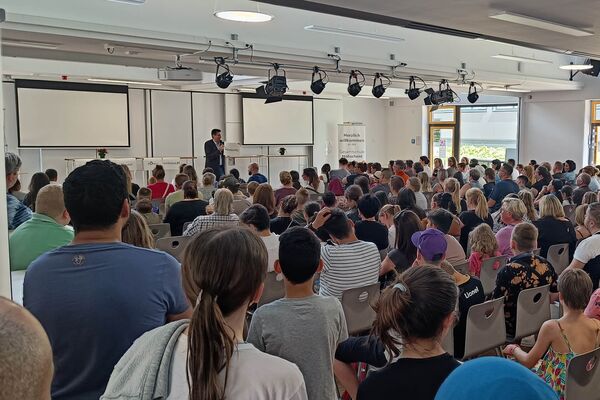 Der Schulleiter begrüßt die neuen Schülerinnen und Schüler mit Eltern in der Mensa. Der Schulleiter begrüßt die neuen Schülerinnen und Schüler mit Eltern in der Mensa.