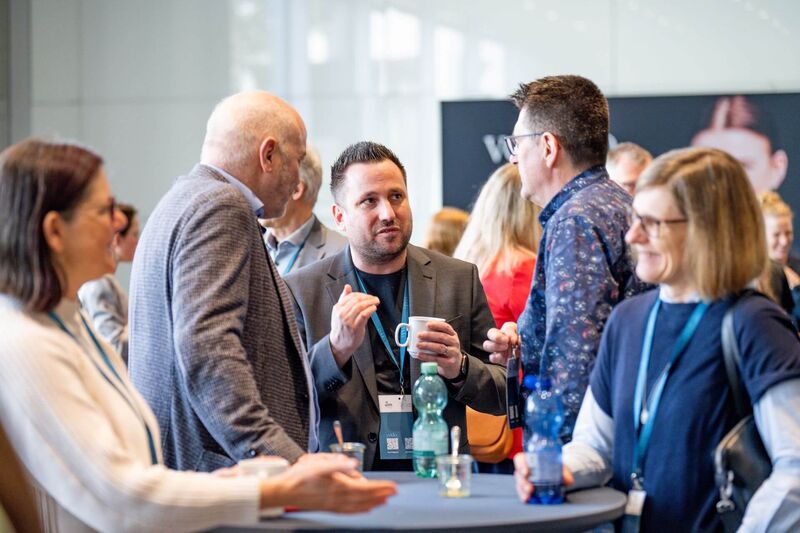 Herr Braun tauscht sich in der Kaffeepause mit drei anderen Kongressteilnehmern angeregt aus.